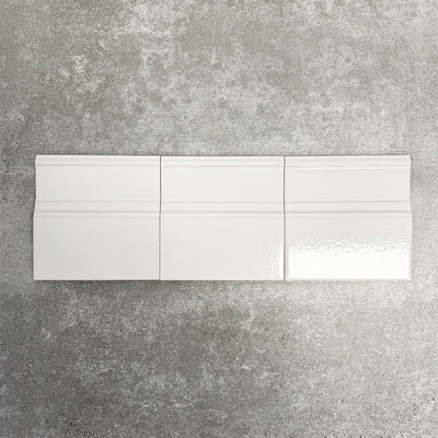 Pimlico White 15 × 15cm ceramic skirting tiles with a crackle glaze finish, featuring soft white tones and moulded detailing, designed to create a neat transition between tiled walls and floors.