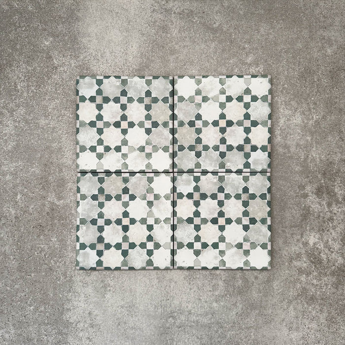 Four Berber Mequinez Green 15×15cm Moroccan-style porcelain tiles arranged together, highlighting the soft green and cream geometric pattern on a neutral background.