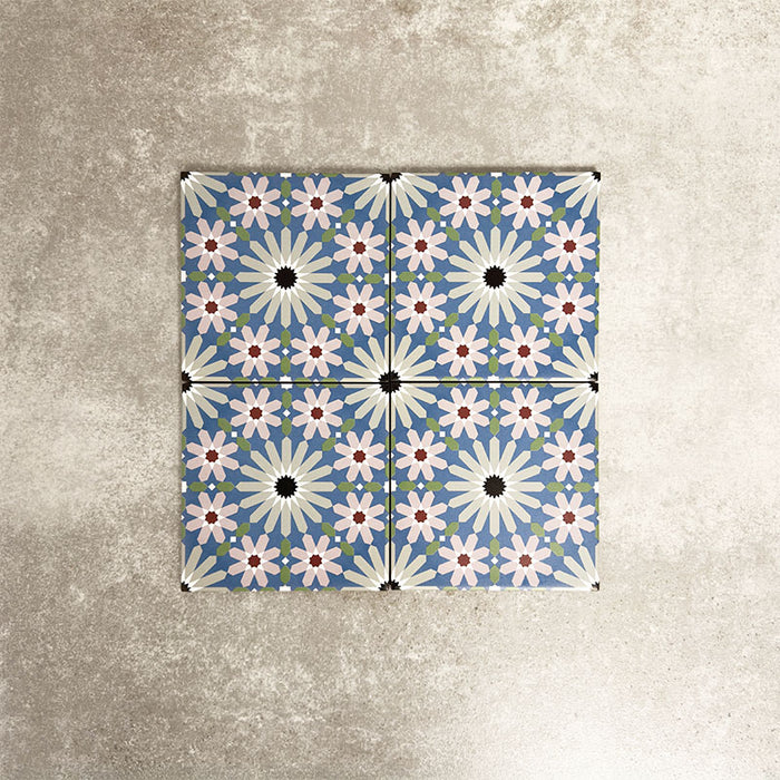 Fez Mini Artisan 15x15cm Moroccan-style porcelain tile displayed against a textured grey background, highlighting the intricate multicolour geometric star pattern in soft blue, blush pink, green and terracotta tones with an encaustic-inspired finish.
