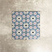 Fez Mini Artisan 15x15cm Moroccan-style porcelain tile displayed against a textured grey background, highlighting the intricate multicolour geometric star pattern in soft blue, blush pink, green and terracotta tones with an encaustic-inspired finish.