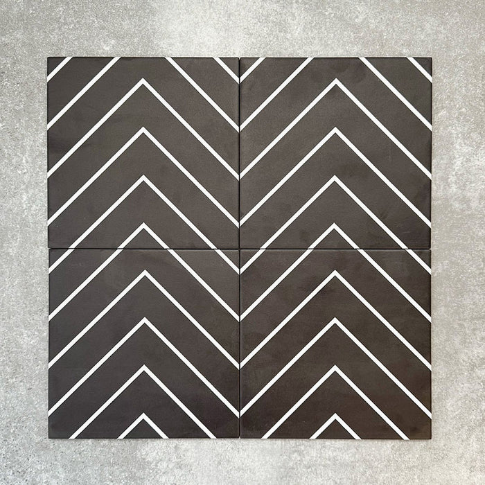 Four Almeria Jilani Black Moroccan-style porcelain wall and floor tiles arranged together to form a continuous white line chevron pattern on a black base, 20x20cm.