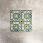 Fez Mini Summer 15x15cm Moroccan-style porcelain tile displayed against a textured grey background, highlighting the colourful geometric star pattern in soft green, blue and blush pink tones with an encaustic-inspired finish.