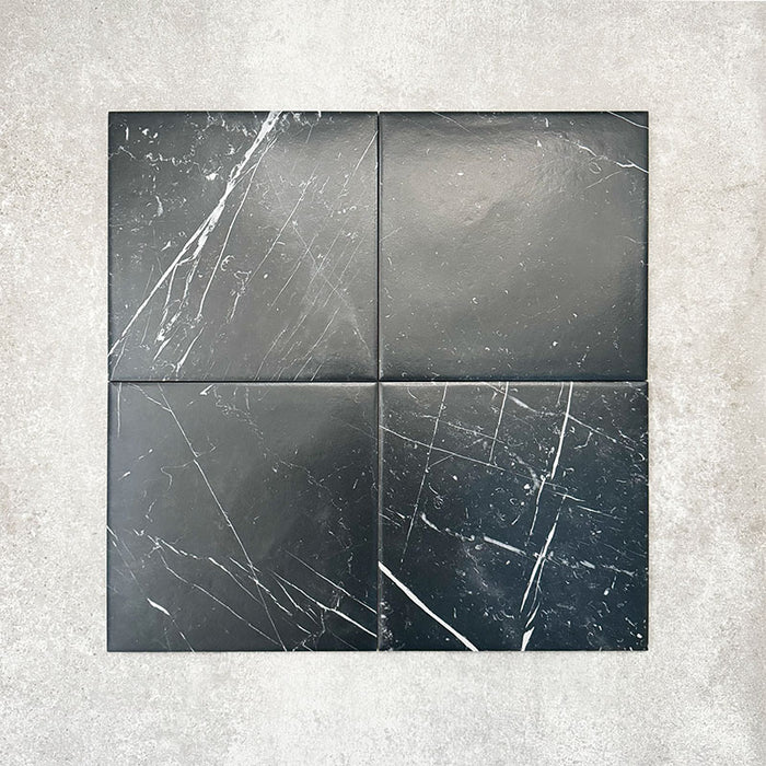 Four Florence Marquina Black 25x25cm marble-effect porcelain tiles displayed together, highlighting the natural variation in veining and tonal depth across the black marble-look surface.