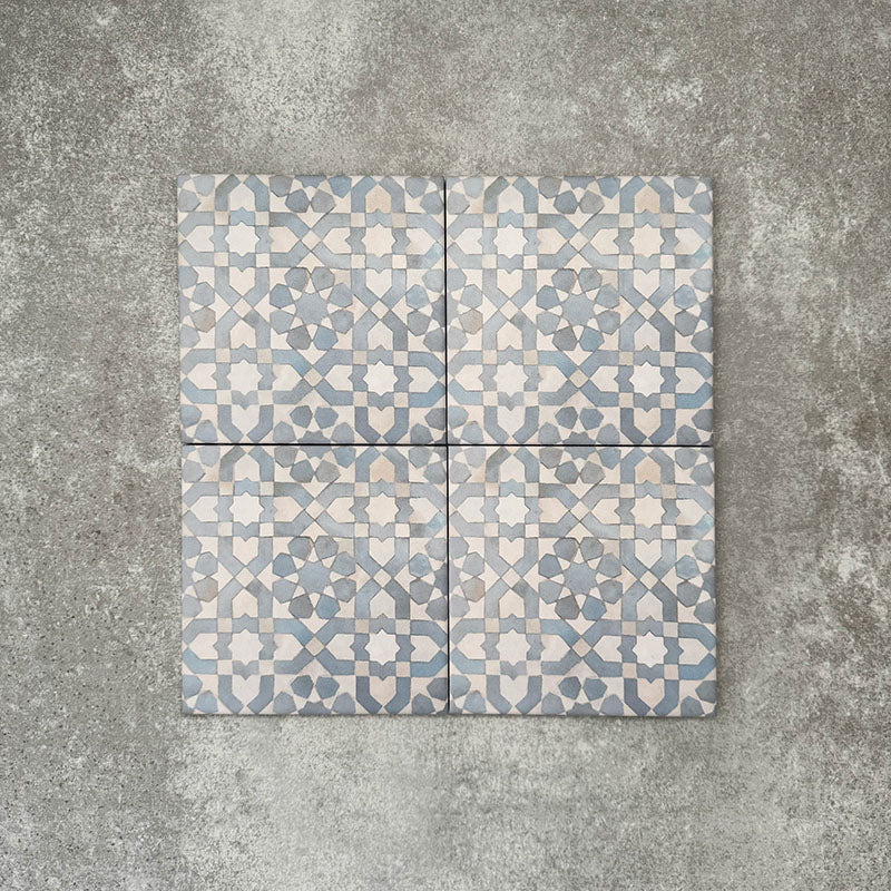 Four Berber Tetuan Blue 15×15cm Moroccan-style porcelain tiles arranged together, highlighting the soft blue and cream geometric pattern on a neutral background.