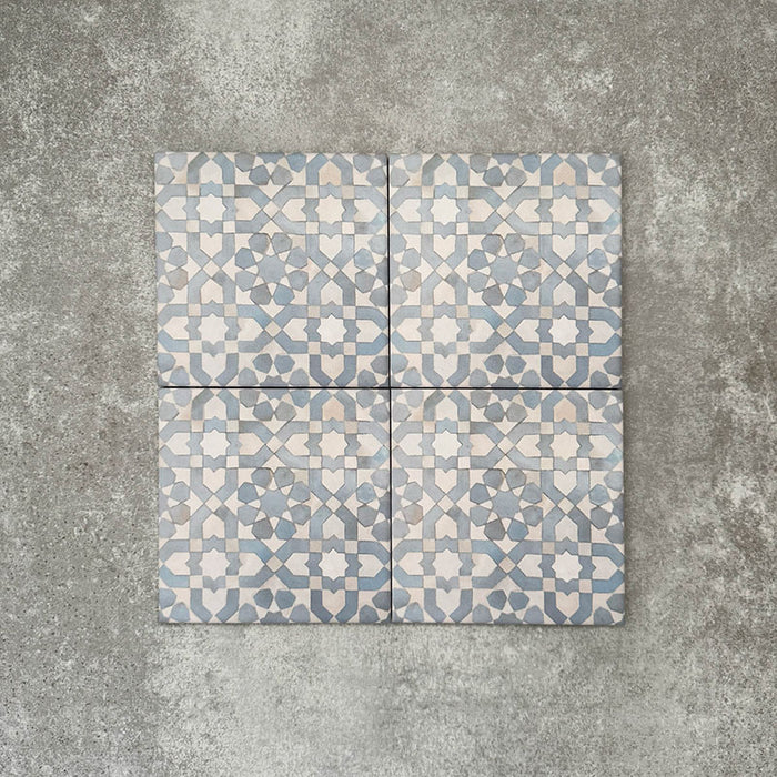 Four Berber Tetuan Blue 15×15cm Moroccan-style porcelain tiles arranged together, highlighting the soft blue and cream geometric pattern on a neutral background.