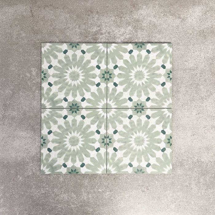 Fez Jade Green 20x20cm Moroccan-style porcelain tile displayed against a textured grey background, highlighting the soft green geometric star pattern and traditional encaustic-inspired design.
