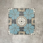 Four Nantes Azul Blue Moroccan-style tiles arranged to show the full pattern repeat. The 20x20cm tiles combine soft blue floral motifs with a central circular mosaic detail in cream, grey and stone tones, forming a symmetrical, traditional Moroccan-inspired design suitable for floors and walls.
