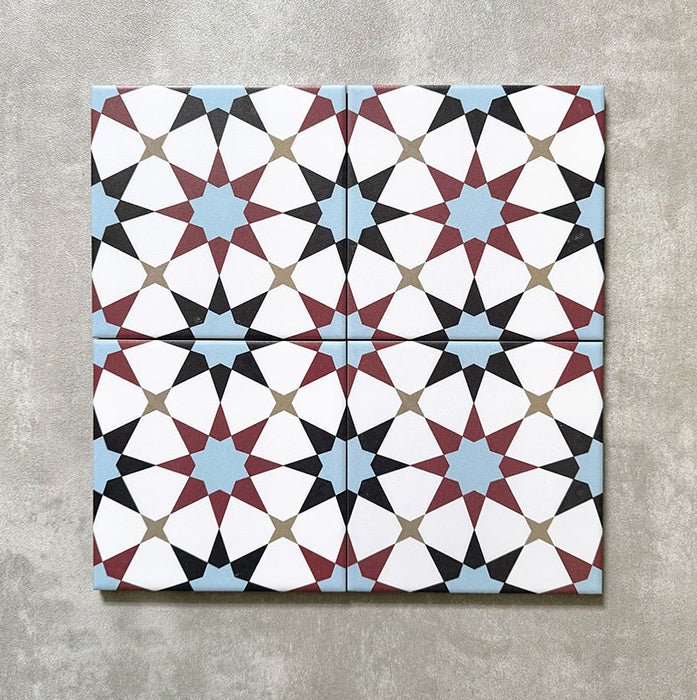 Agadir Atlas Mini Moroccan-style 15x15cm porcelain tiles arranged as four tiles, showcasing a repeating geometric star pattern in soft blue, burgundy, black and cream on a neutral background.