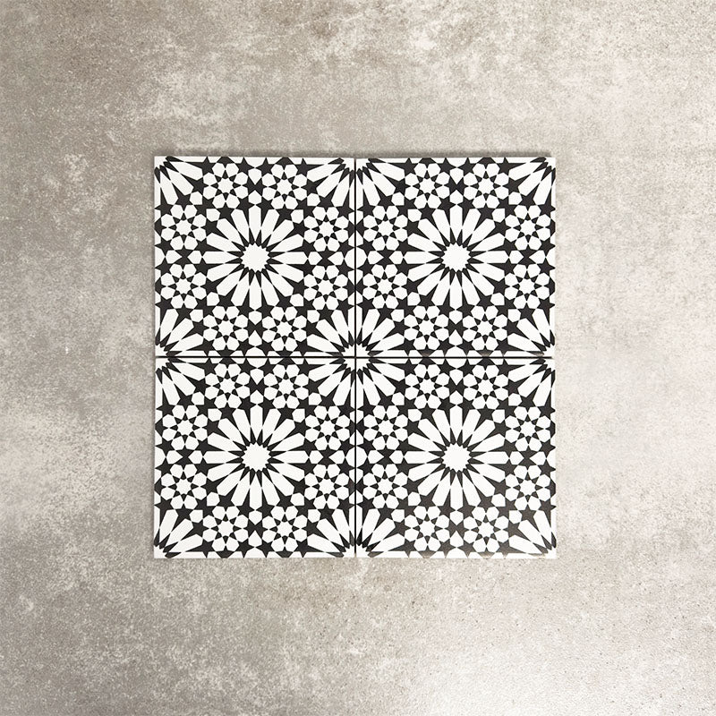 Fez Mini Winter Moroccan-style porcelain tile, featuring an intricate black and white geometric star pattern inspired by traditional Moroccan design. The 15 × 15cm square format highlights the fine encaustic-effect detailing and strong contrast, making it ideal for creating striking feature walls, splashbacks, or patterned floors in both contemporary and classic interiors.
