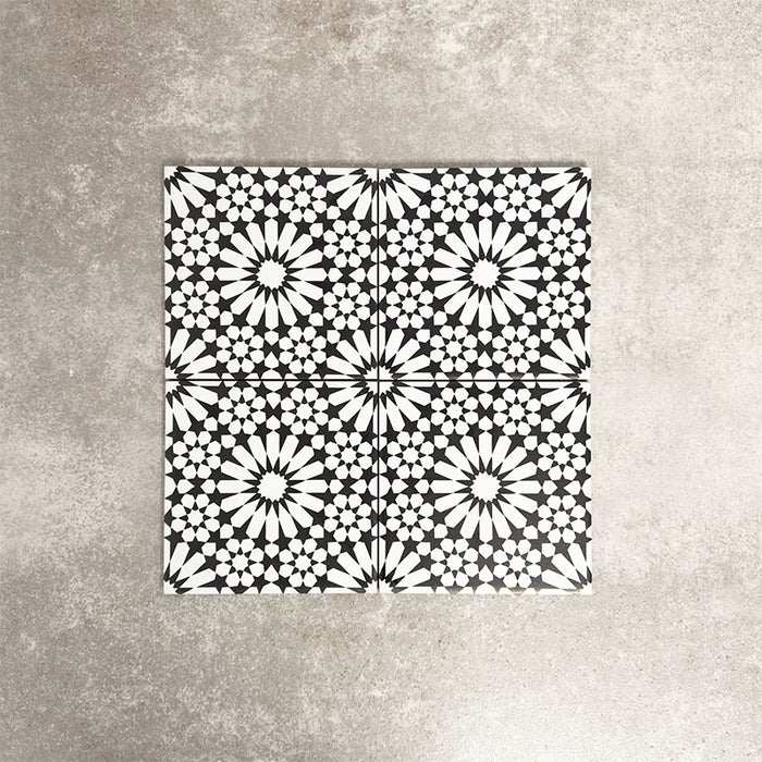 Fez Mini Winter Moroccan-style porcelain tile, featuring an intricate black and white geometric star pattern inspired by traditional Moroccan design. The 15 × 15cm square format highlights the fine encaustic-effect detailing and strong contrast, making it ideal for creating striking feature walls, splashbacks, or patterned floors in both contemporary and classic interiors.