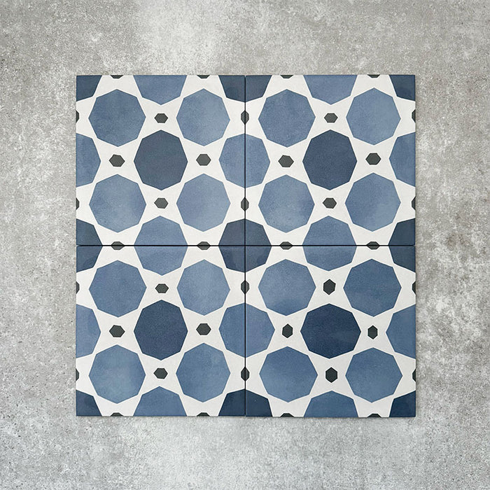 Viscount Sapphire 20×20cm Victorian-style porcelain wall and floor tiles laid in a repeating blue and white geometric pattern, shown as a full tile layout with octagonal motifs and subtle tonal variation, styled with white floral accents.