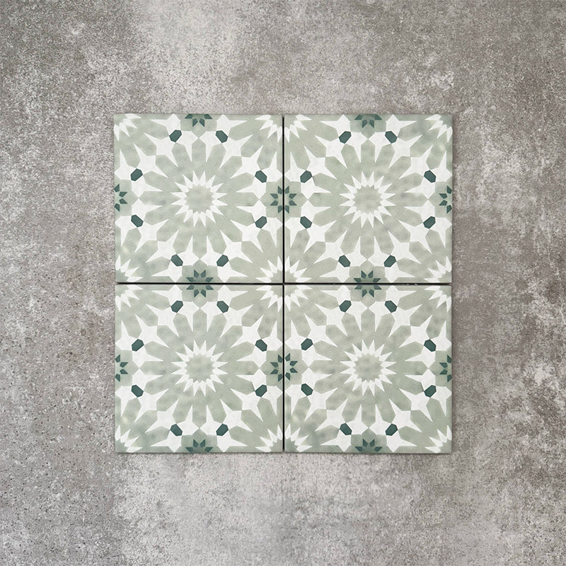 Fez Mini Jade Green 15x15cm Moroccan-style porcelain tile displayed against a textured grey background, highlighting the soft jade green and white geometric star pattern with an encaustic-inspired finish.