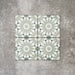 Fez Mini Jade Green 15x15cm Moroccan-style porcelain tile displayed against a textured grey background, highlighting the soft jade green and white geometric star pattern with an encaustic-inspired finish.