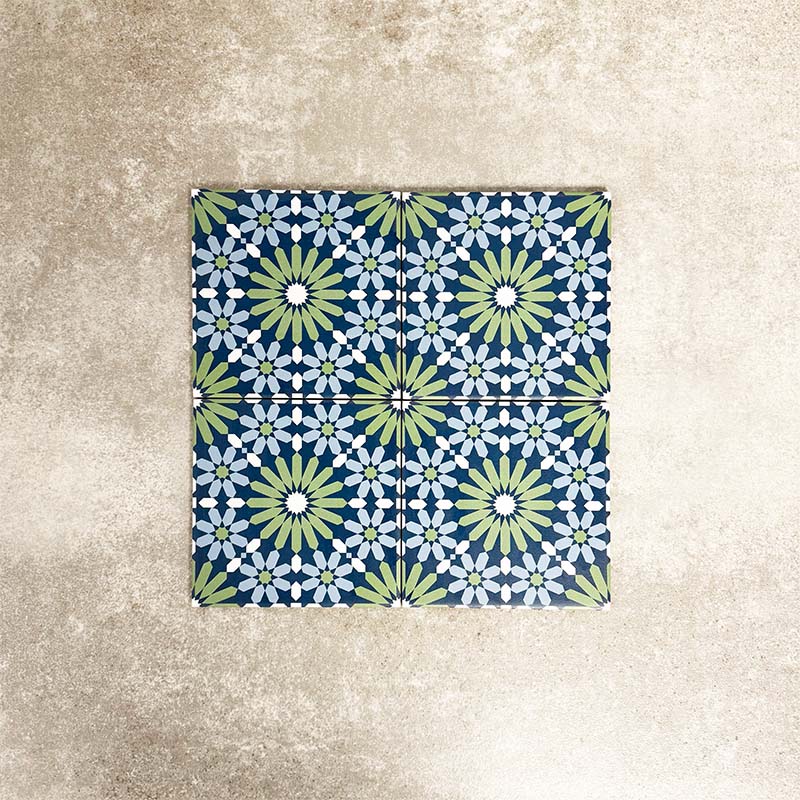 Fez Mini Springs 15x15cm Moroccan-style porcelain tiles arranged as a four-tile panel, highlighting the full repeat design with layered blue and soft green geometric star motifs against a textured grey background.