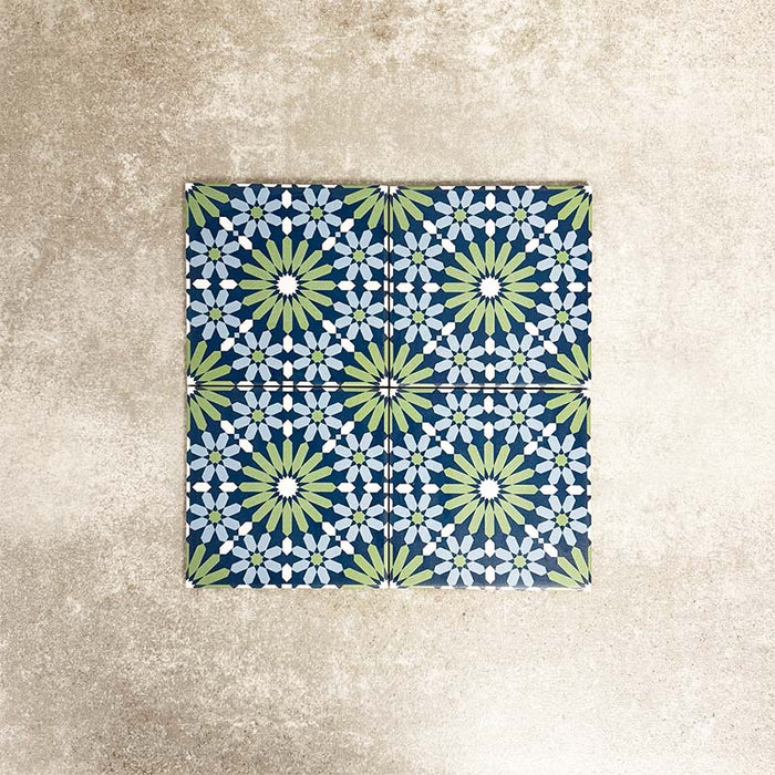Fez Mini Springs 15x15cm Moroccan-style porcelain tiles arranged as a four-tile panel, highlighting the full repeat design with layered blue and soft green geometric star motifs against a textured grey background.