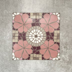 Nantes Rose Pink Moroccan-style patterned tiles laid in a seamless layout, showcasing soft pink floral motifs, cream circular medallion details, and mosaic-inspired geometric accents in muted neutrals and deep burgundy tones. The 20x20cm encaustic-style tiles create a decorative, vintage-inspired surface ideal for floors or feature walls.