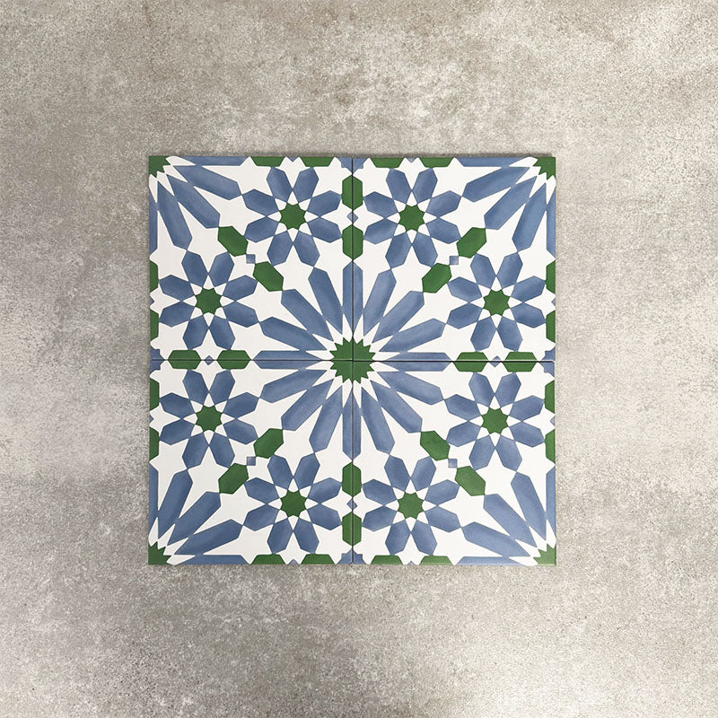 Fez Ocean Blue 20x20cm Moroccan-style porcelain tiles arranged as a four-tile panel, highlighting the blue, white and green geometric star pattern and the full repeat design against a textured grey background.