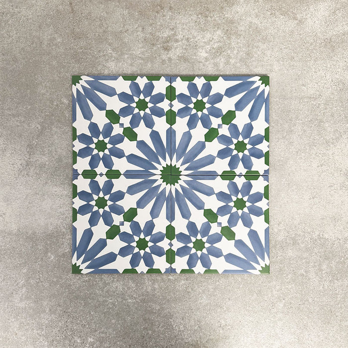 Fez Ocean Blue 20x20cm Moroccan-style porcelain tiles arranged as a four-tile panel, highlighting the blue, white and green geometric star pattern and the full repeat design against a textured grey background.