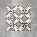 Viscount Turner 20×20cm Victorian-style porcelain wall and floor tiles laid in a repeating geometric pattern with cross and floral-inspired motifs in soft blue, white, grey and warm beige tones, shown as a full tile layout with subtle tonal variation and floral styling.