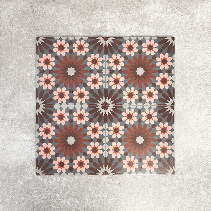 Fez Rosso Moroccan-style porcelain tile, highlighting the intricate geometric pattern in full detail. Deep terracotta and earthy red tones radiate from the centre, layered with soft blush pink star motifs and set against a muted grey background. The balanced, symmetrical design draws inspiration from traditional Moroccan tilework while the porcelain finish keeps it practical and durable. A bold yet elegant choice, ideal for creating feature floors, splashbacks or statement walls with warmth and character.