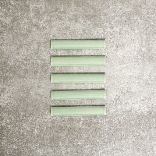 Pimlico Lime Green pencil trim tiles measuring 2.5 × 15cm, featuring a crackle glaze finish and soft green tone, designed to neatly frame wall tiles and create a polished edge in bathrooms and kitchens.