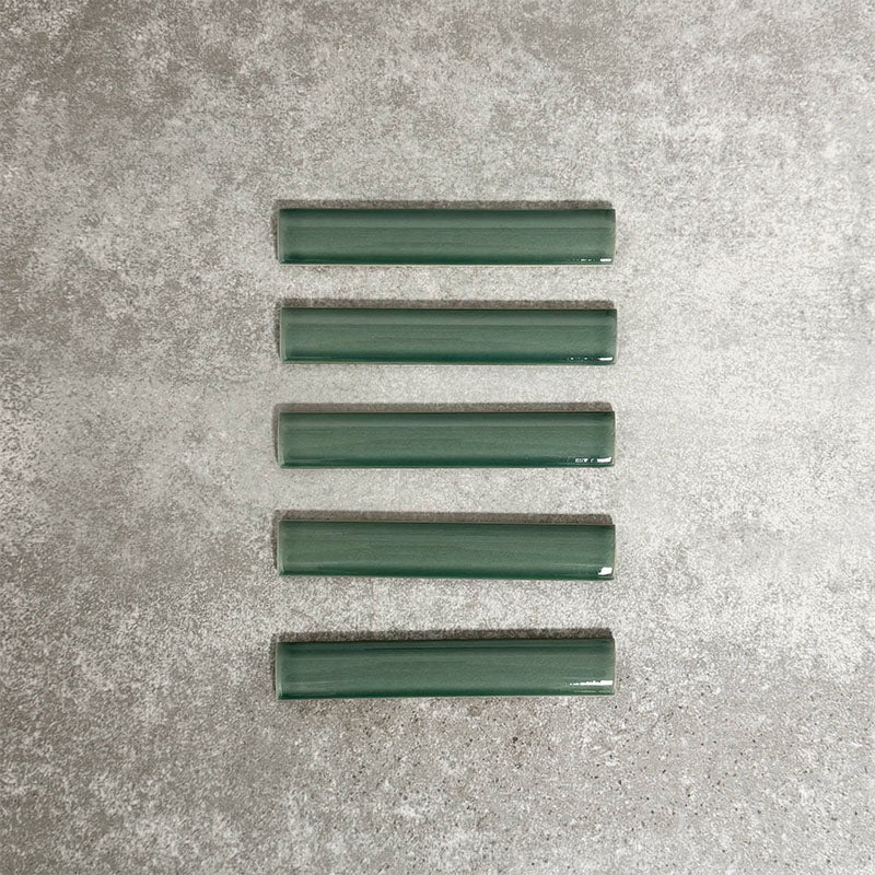 Pimlico Golders Green pencil trim tiles measuring 2.5 × 15cm, finished with a crackle glaze and deep green tone, designed to neatly frame ceramic wall tiles and add a subtle decorative edge.