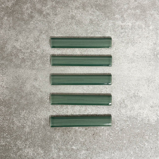 Pimlico Golders Green pencil trim tiles measuring 2.5 × 15cm, finished with a crackle glaze and deep green tone, designed to neatly frame ceramic wall tiles and add a subtle decorative edge.