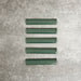 Pimlico Golders Green pencil trim tiles measuring 2.5 × 15cm, finished with a crackle glaze and deep green tone, designed to neatly frame ceramic wall tiles and add a subtle decorative edge.