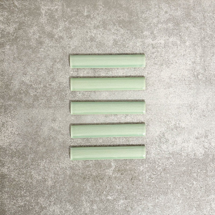 Pimlico Lime Green pencil trim tiles measuring 2.5 × 15cm, featuring a crackle glaze finish and soft green tone, designed to neatly frame wall tiles and create a polished edge in bathrooms and kitchens.