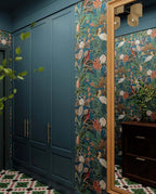 Hallway interior featuring Abstract Compass Green 20x20cm patterned floor tiles in green, white and red tones, styled with teal panelling, botanical wallpaper, wooden console table, and decorative accessories in a characterful entrance space.