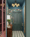 Hallway interior featuring Abstract Compass Green 20x20cm patterned floor tiles in green, white and red tones, styled with teal panelling, botanical wallpaper, wooden console table, and decorative accessories in a characterful entrance space.