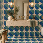 Contemporary bathroom featuring Abstract Ocean 20x20cm patterned wall and floor tiles, with bold blue and teal geometric circles against a soft pink background, paired with a terrazzo-effect basin, brass fittings and natural wooden accessories.