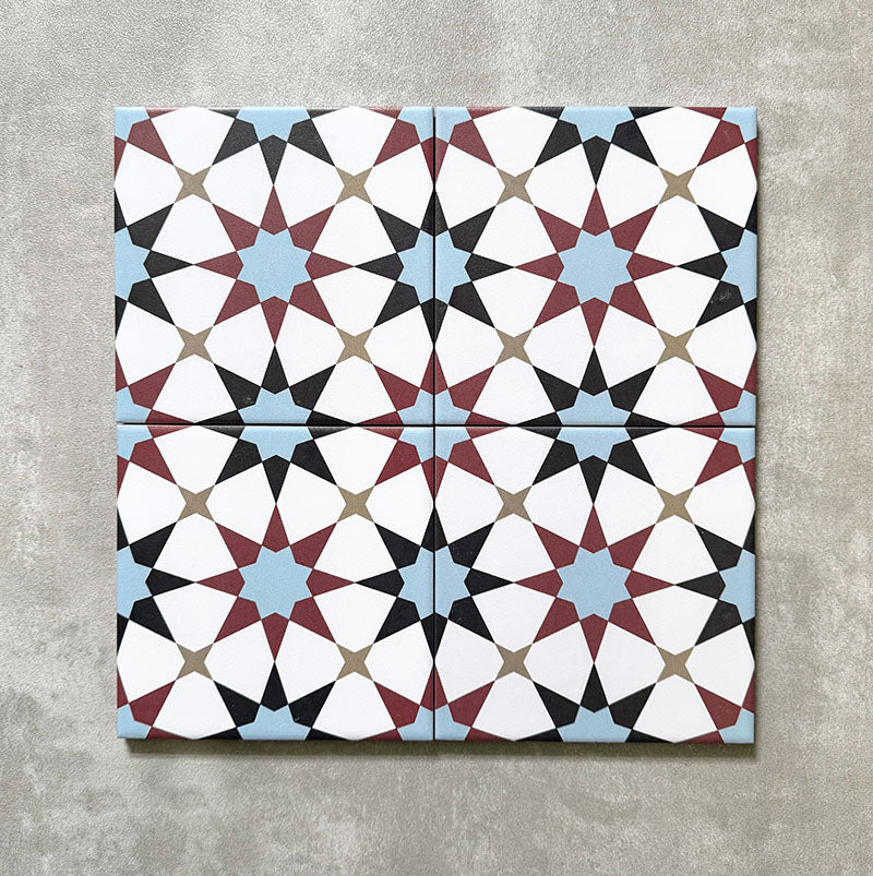 Agadir Atlas Mini Moroccan-style 15x15cm porcelain tiles arranged as four tiles, showcasing a repeating geometric star pattern in soft blue, burgundy, black and cream on a neutral background.
