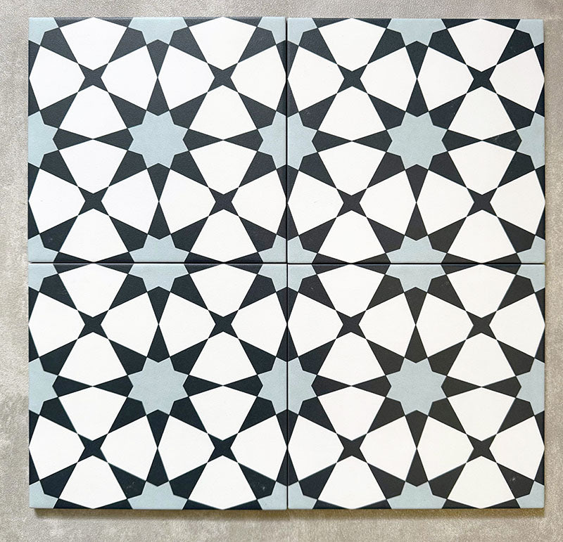 Agadir Azul Blue Moroccan-style 20x20cm porcelain tiles arranged as four tiles, showcasing a repeating geometric star pattern in blue, black and white on a neutral background.
