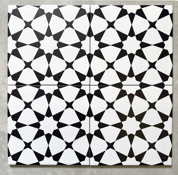 Agadir Black & White Moroccan-style 20x20cm porcelain tiles arranged as four tiles, showcasing a repeating geometric star pattern in black and white on a neutral background.