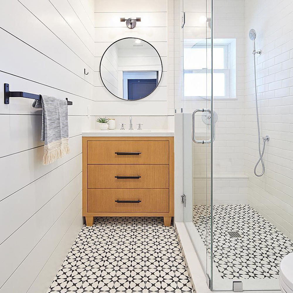 Bathroom interior featuring Agadir Black & White Mini Moroccan-style 15x15cm porcelain floor tiles, showcasing a bold geometric star pattern, styled with a walk-in shower, wooden vanity unit and crisp white walls.
