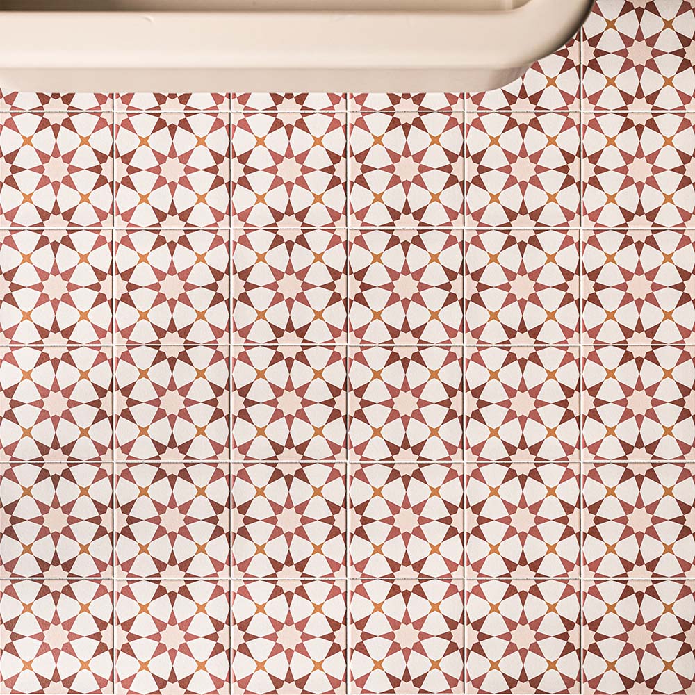 Agadir Cotto 20cm x 20cm Moroccan style tiles, showcasing an intricate geometric star pattern in warm terracotta, burgundy and white tones, creating a bold repeating design across the bathroom floor.