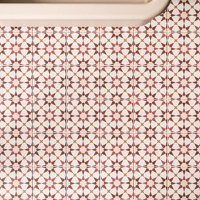 Agadir Cotto 20cm x 20cm Moroccan style tiles, showcasing an intricate geometric star pattern in warm terracotta, burgundy and white tones, creating a bold repeating design across the bathroom floor.