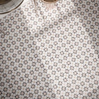 Close-up of Agadir Natural 20x20cm Moroccan-style patterned bathroom floor tiles, featuring intricate geometric star motifs in cream, grey, black and beige, arranged in a repeating decorative design.
