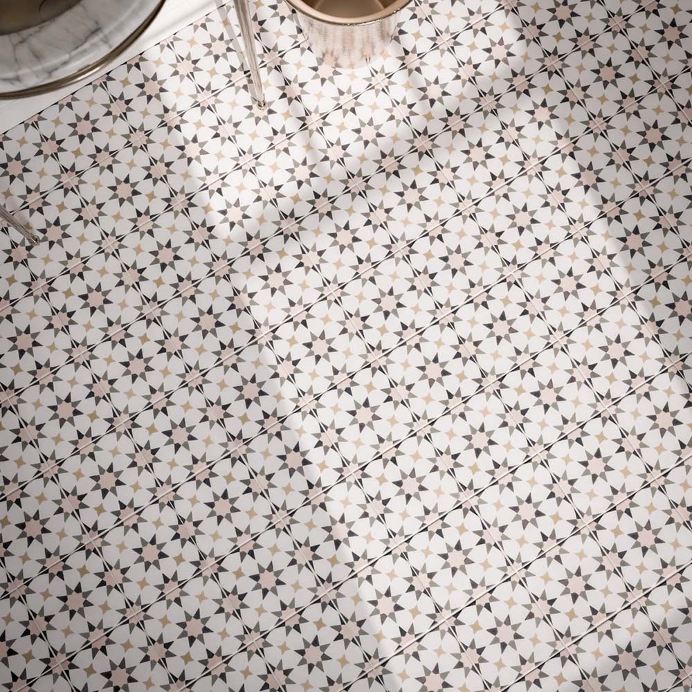 Close-up of Agadir Natural 20x20cm Moroccan-style patterned bathroom floor tiles, featuring intricate geometric star motifs in cream, grey, black and beige, arranged in a repeating decorative design.