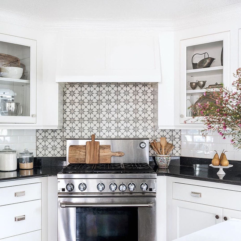 Agadir Silver Moroccan-style 20x20cm porcelain tiles used as a kitchen splashback, showcasing a subtle grey and white geometric pattern behind a stainless steel range cooker in a bright white kitchen.