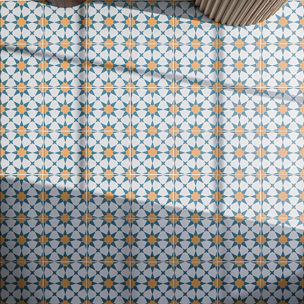 Close-up of Agadir Sun and Sky 20x20cm Moroccan-style patterned floor tiles, featuring vibrant blue, orange and white geometric star motifs arranged in a repeating design, creating a colourful and decorative finish.