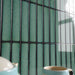 Close-up of Alchemy Hunter Green 6.5cm x 30cm wall tiles laid vertically, highlighting the rich green glaze, dark edging and distinctive speckled surface variation with a glossy finish.