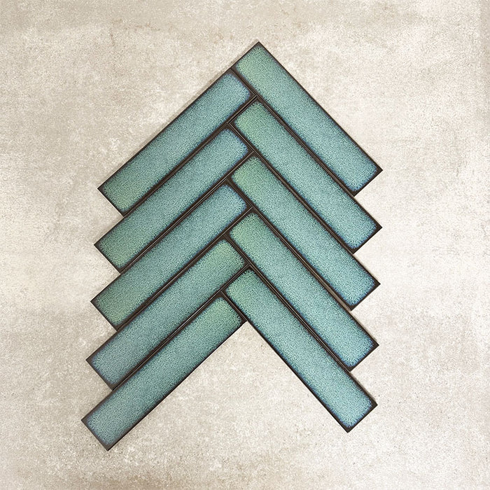Alchemy Hunter Green 6.5×30cm ceramic wall tiles arranged in a herringbone pattern with a glossy green finish.