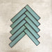 Alchemy Hunter Green 6.5×30cm ceramic wall tiles arranged in a herringbone pattern with a glossy green finish.