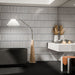 Bathroom featuring Alchemy Magma White 6.5cm x 30cm wall tiles laid vertically, showcasing a soft white finish with contrasting dark edging, paired with a black freestanding bath and contemporary stone-effect vanity.