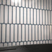 Close-up of Alchemy Magma White 6.5cm x 30cm wall tiles laid vertically, highlighting the soft white surface, rounded edges and distinctive dark blue edging.