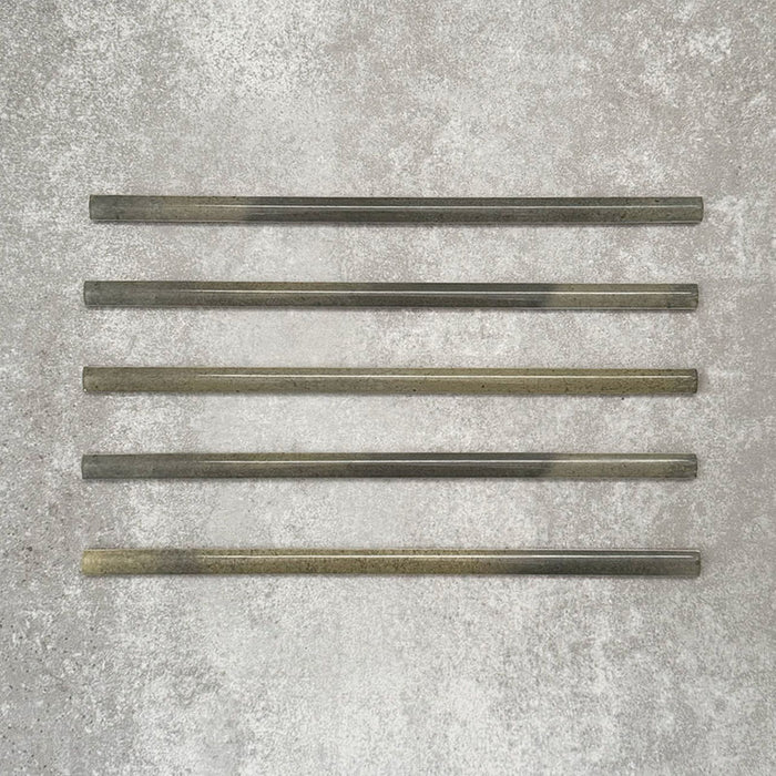 Five Allegra Daisy Green Gloss pencil bullnose border ceramic tiles in a 1.2 × 30cm format, laid horizontally to showcase the slim profile, glossy finish and subtle natural green tonal variations across the set.