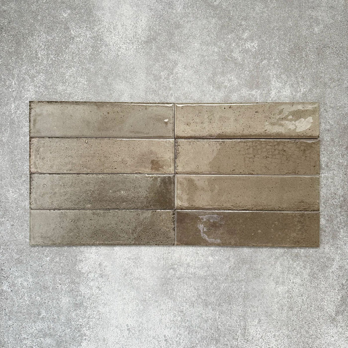 Allegra Sage Green Gloss Brick ceramic tiles in a 6 × 25cm format, laid horizontally to highlight the muted green tones, glossy finish and subtle handmade-style surface variation.