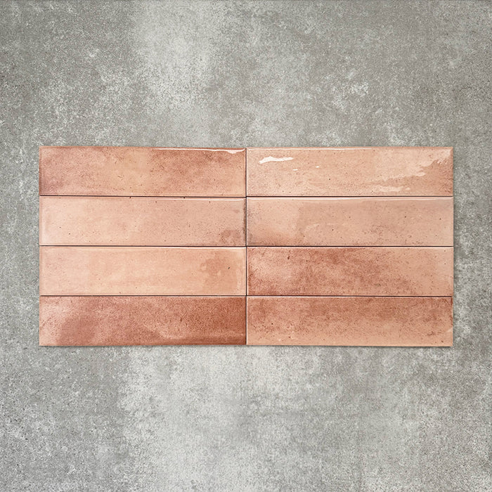 Allegra Tusk Pink Gloss Brick ceramic tiles in a 6 × 25cm format, laid horizontally to highlight the warm pink tones, glossy finish and subtle handmade-style variation.